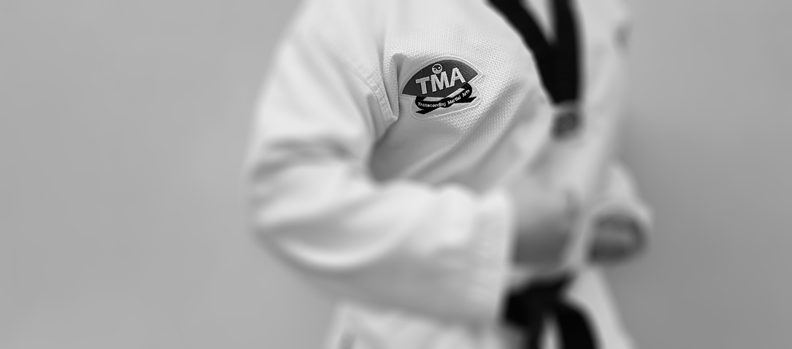 Person in Taekwondo uniform showing Transcending Martial Arts logo on chest