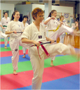 Group of adults in kicking taekwondo pose at Transcending Martial Arts